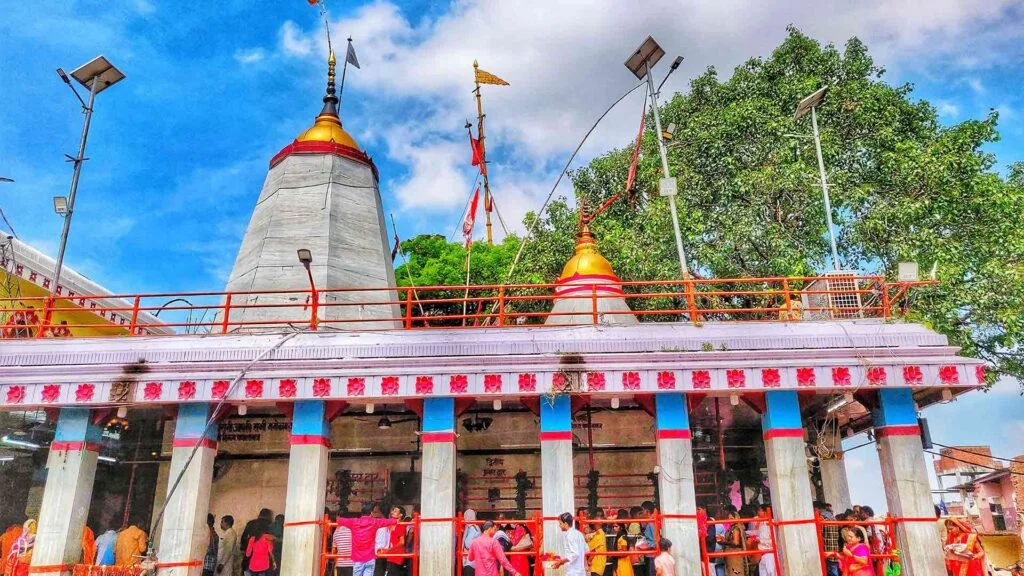 समय के माध्यम से यात्रा: विंध्याचल मंदिर के समृद्ध इतिहास को उजागर करना 2 A banner promoting the Vindhyachal temple, a Hindu temple located in Vindhyachal, India. The image shows a group of people performing aarti, a Hindu ritual of worship, in front of the temple. The temple's main structure with its towers and spires is visible in the background. The text on the banner reads 'Welcome to Vindhyachal Temple' and 'Experience the Divine